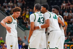 Baylor men's basketball players huddle on the court.